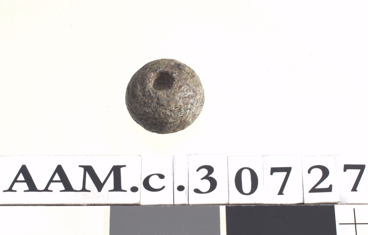Lite spinnehjul av kleberstein, av type som Vikingetidens Redskaper, fig. 164, men noe mindre. - Tverrmål 3 cm.