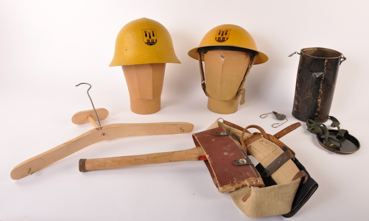 Gruppering fra Halden sivilforsvar, bestående av 2 hjelmer i stål, en beholder, en brannøks, og en kleshenger.