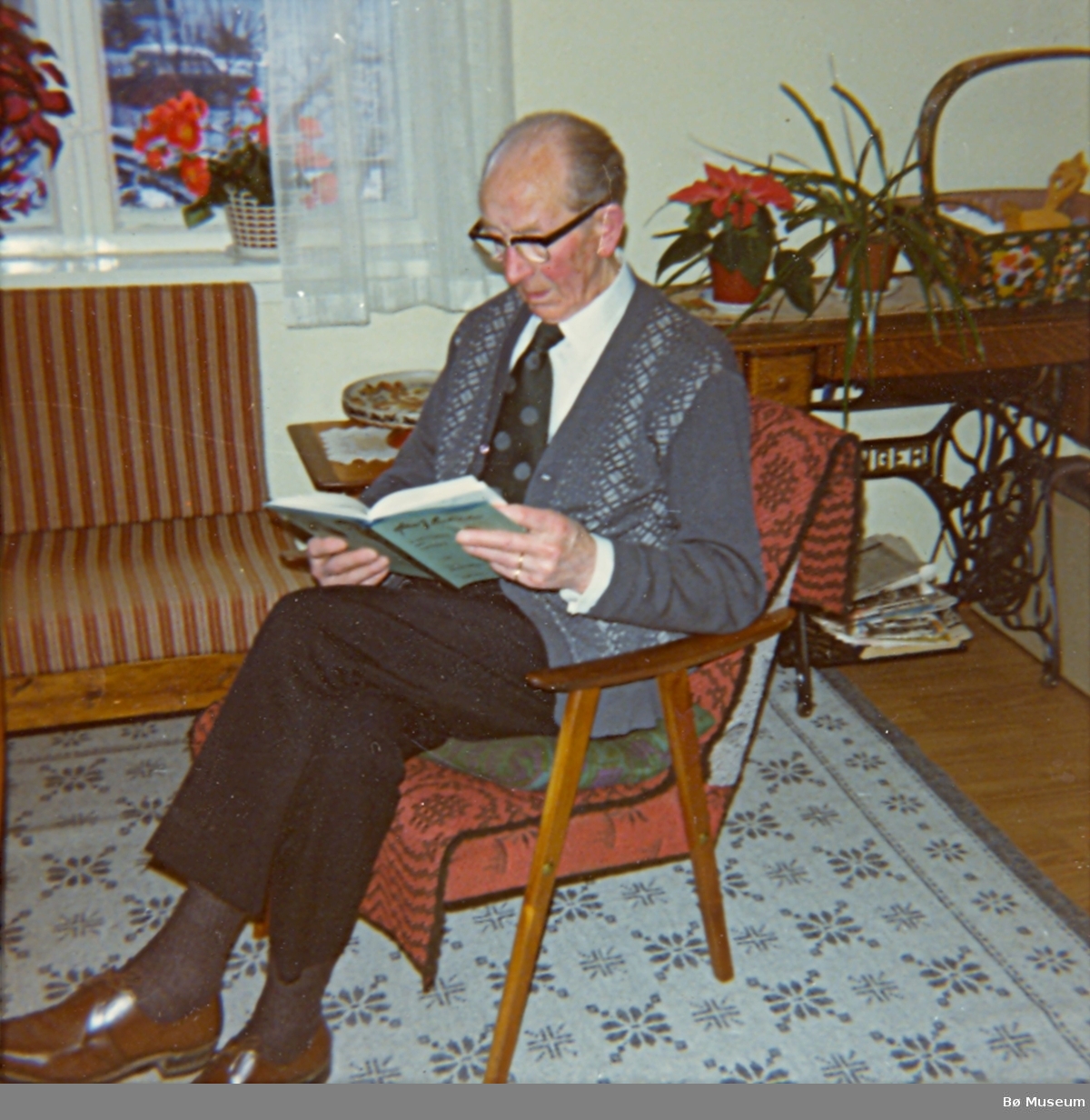 Halvor Storhaug sit og les i lenestol, nyttårsaften 1977