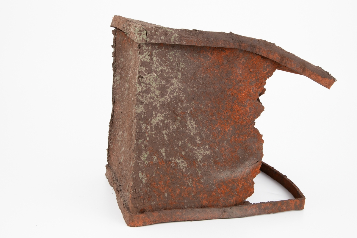 Håndlaget keramikkskulptur som imiterer rustent metall. Formen ligner en boks som ligger med åpningen på siden, delvis sammentrykt, hullete og erodert. Frynsete, skarpe kanter.