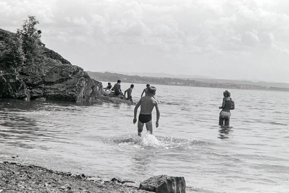 Svart-hvitt foto av barn som bader ved et skjær i Mjøsa.