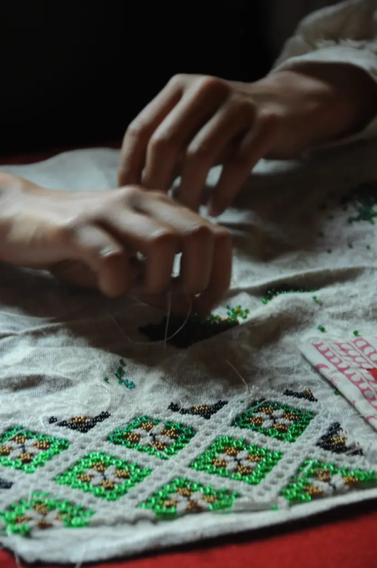 Nærbilde av hender som arbeider med perler