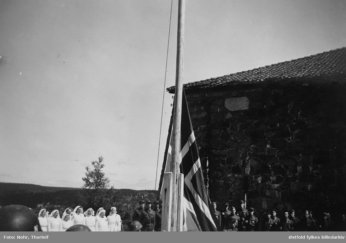 Frigjøringsdagene i Halden i mai 1945, etter andre verdenskrig. Flaggheising på Fredriksten festning. Sykepleiere i bakgrunnen.