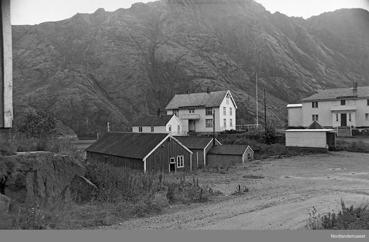 Bygninger i fiskeværet Nusfjord. Boliger, uthus og rorbuer. Fjellskråning i bakgrunnen.