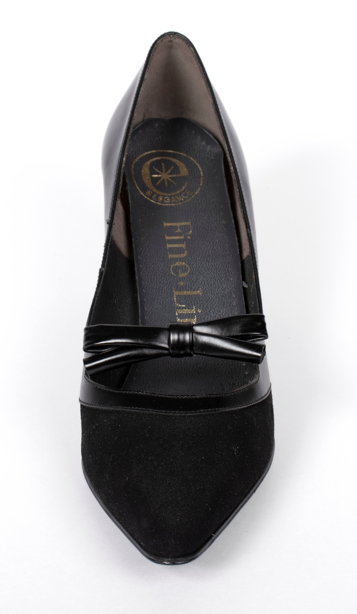 En sort damesko i glatt skinn med en sløyfe der fremste delen av skoen er i semsket skinn
