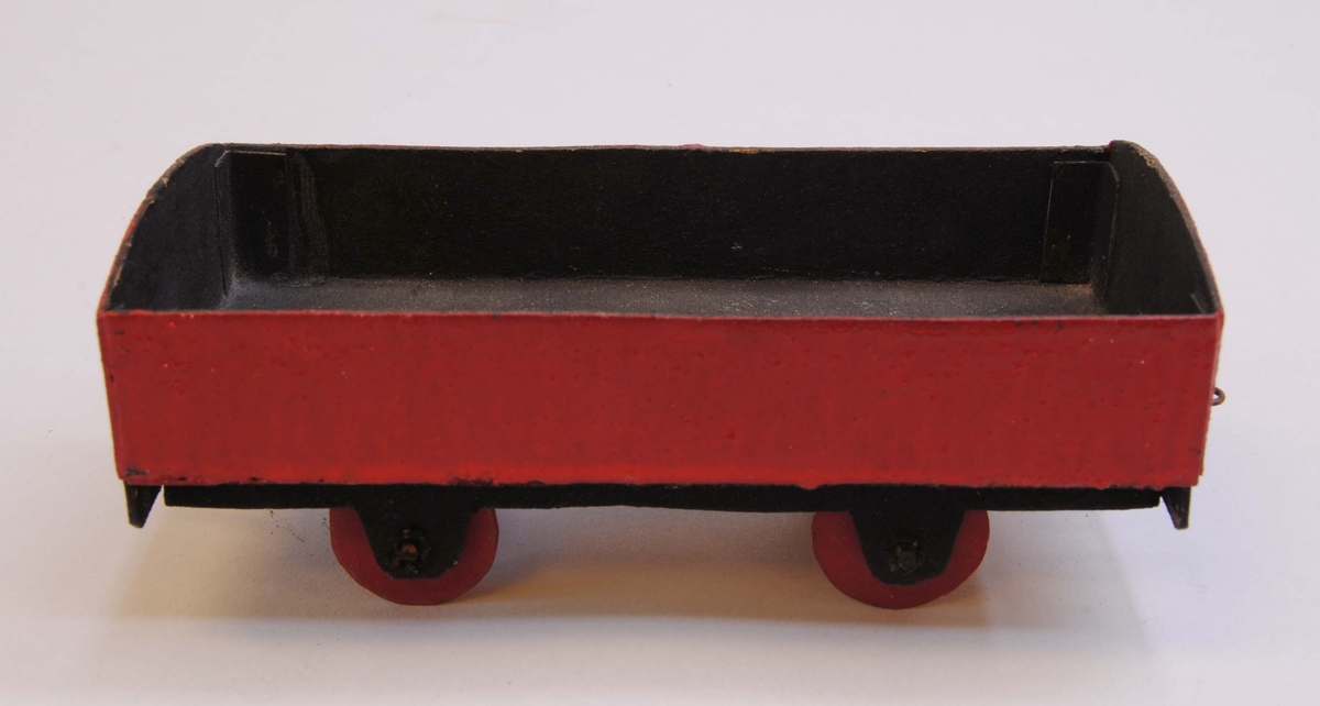 Öppen godsvagn av papp. Delarna är limmade eller sammanfogade med rött lack.
Hjulen är gjorda av papp och hjulaxlarna av runda träpinnar. Vagnen är målad röd på utsidan med svart insida, underrede och röda hjul.
Under vagnen är datumet "28/12 1918" handskrivet. På ena kortsidan av vagnen finns en ögla och på andra sidan en hake av ståltråd för att koppla samman vagnen med andra vagnar eller lok.