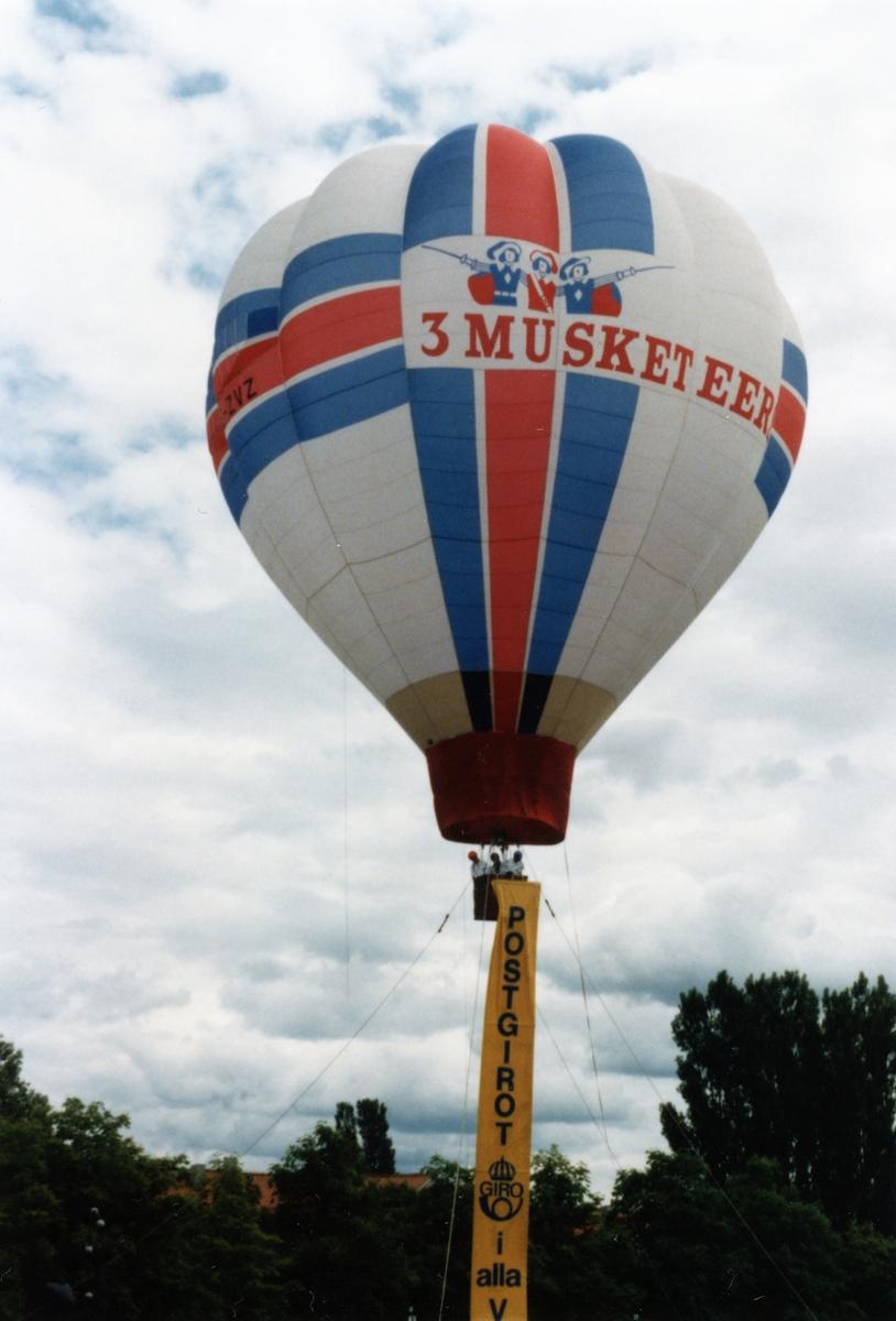 Folkets Park i Linköping. En luftballong i luften, från korgen hänger en banderoll det står Postgirot på. Troligtvis taget under cykeltävlingen Postgirot Open 1987.