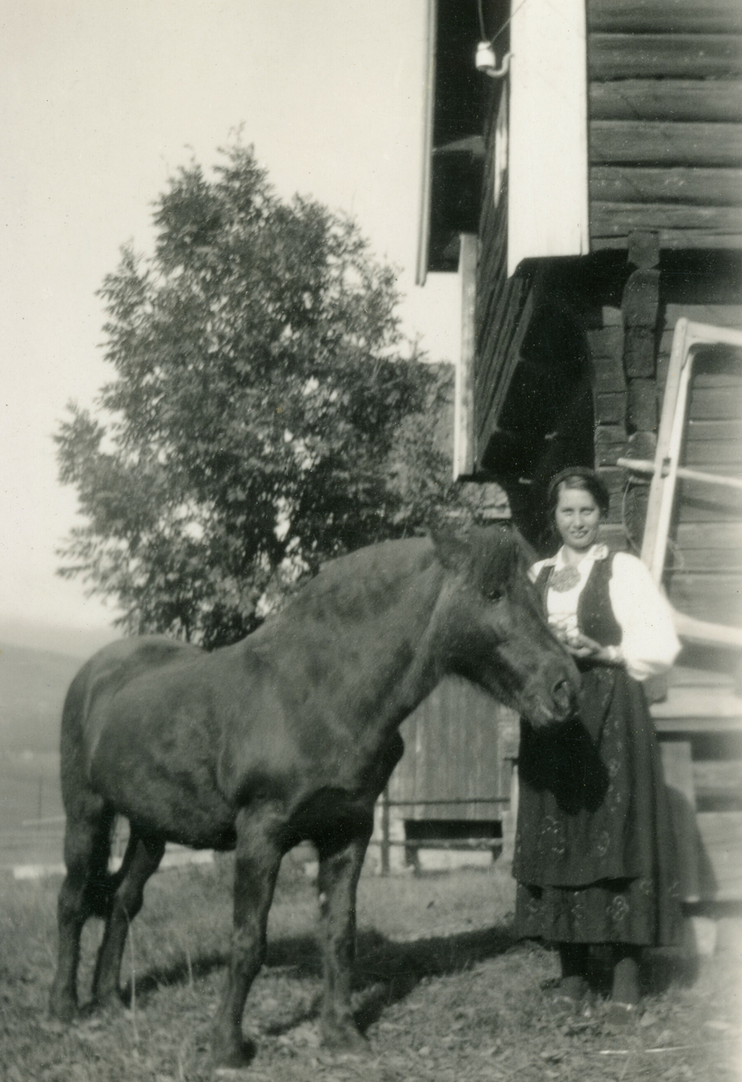 Portrett av kvinne i bunad og ein hest