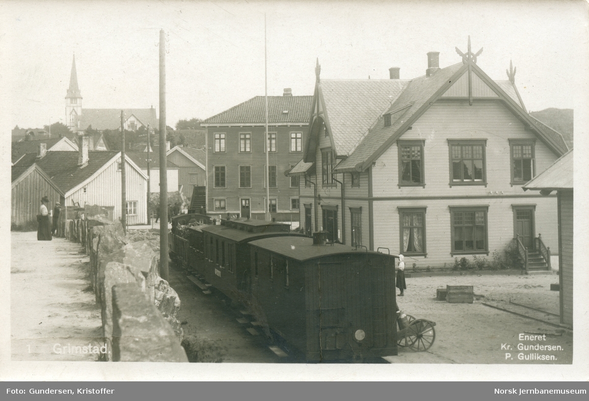 Blandet tog på Grimstad stasjon. Nærmest to vogner tilhørende Grimstad-Frolandsbanen, konduktørvogn litra F og personvogn litra BC, deretter en innlånt karet fra NSB og nærmest lokomotivet en godsvogn litra L
