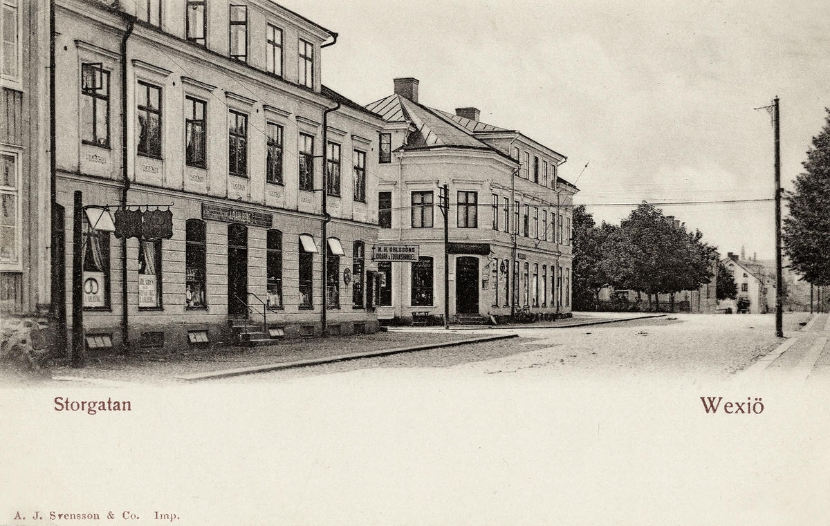 Storgatan, Växjö ca 1905, nästan i korsningen mot Västergatan, med kvarteret Stormen 1 till vänster, följt av hörnfastigheten 
kvarteret Fries 3. I bakgrunden skymtar man Askelyckan m.m.