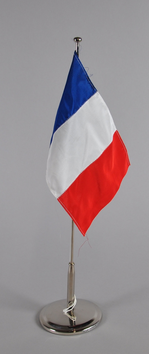 Bordflagg på stang fra Frankrike. Tre vertikale striper, blått nærmest stangen, hvitt i midten og rødt ytterst.