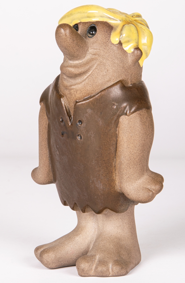 Figurin i flintgods föreställande Barney Granit ur serien "The Flintstones". Formgiven 1957 för Gefle porslin. Detta ex tillverkat mellan 1961-1971 enligt stämpeln.