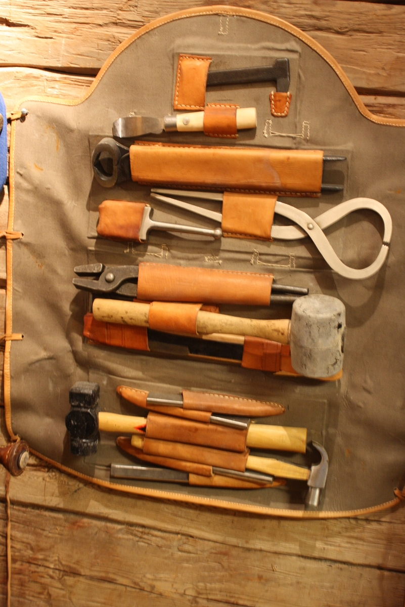 Utfällbar väska av läder och textil fylld med verktyg för hovslagare.
Läderrämmar och metallspännen. 

Märkt m/93