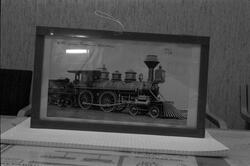 Fotografi av gammelt prærielokomotiv i ramme, som står på en