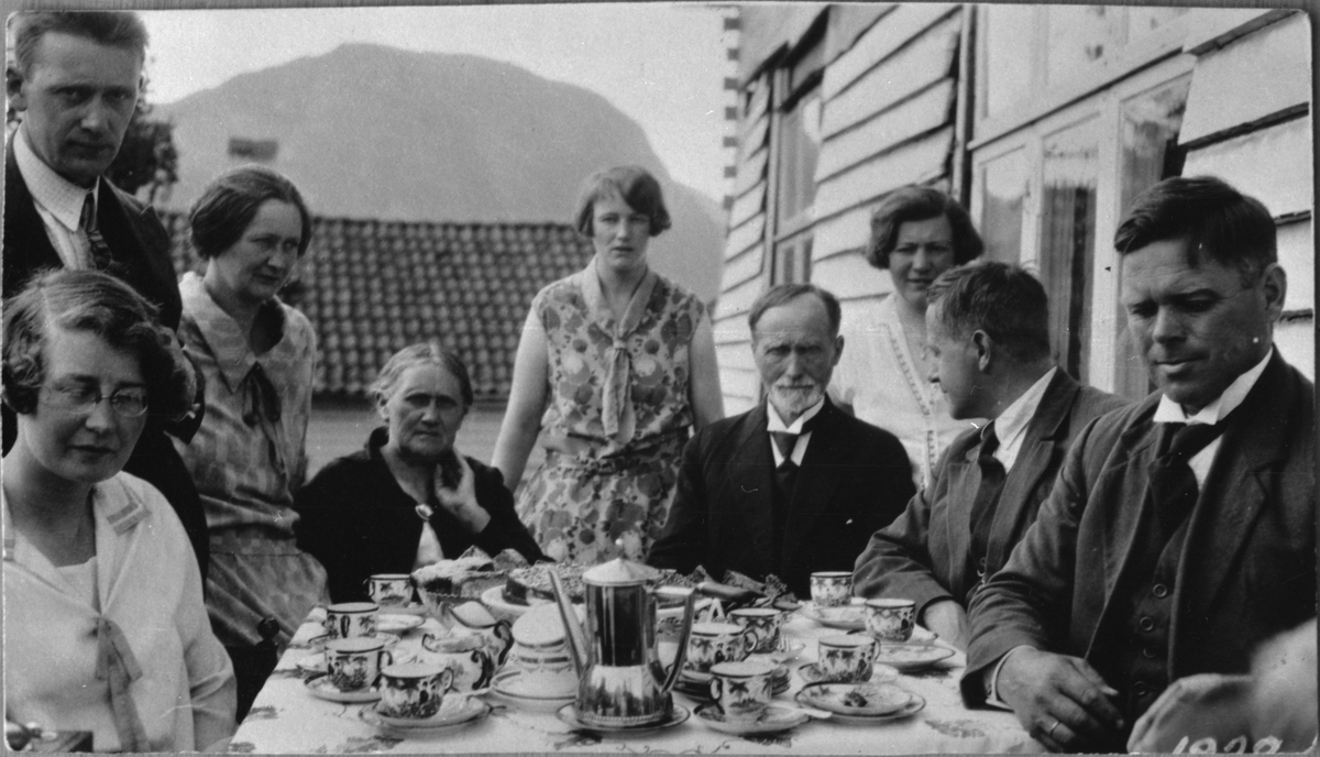 Familien Ekrheim nyter kaffi og kake på terrassen til Ekrheims hotell i Ølensjøen, 1930. Frå venstre: Helga Sverdrup Ekrheim, Olaf Ekrheim, Tulla Ekrheim Hovda, Anna Ekrheim, Agnes Ekrheim Christiansen, Aasmund Ekrheim, Katrine Ekrheim, Toralf Ekrheim og Johs. Hovda.