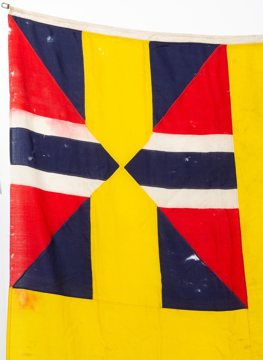 Svensk flagg med unionsmerke, "sildesalaten". Metallhempe. Møllspist og slitt.
Unionsmerket: 120 x 103

Givers datter opplyser at flagget var kjøpt på auksjon eller loppemarked på 1980 tallet. Det skal ha kommet fra båtbyggeriet på Kugrava i Son.