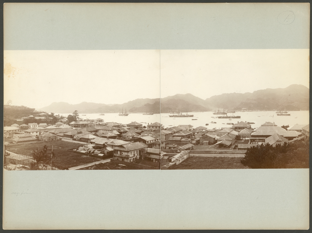 Bilden föreställer en panorama från Nagasaki som är sammansatt av två fotografier. De är tagen från en förhöjd ståndpunkt på kullarna ovan på staden. I förgrunden syns staden låga träbebyggelse och i bakgrunden bukten och hamnen fullt med båtar och skepp. Segelfartyget på vänstra bilden är Vanadis.