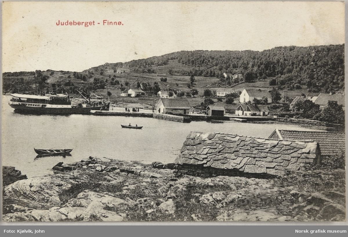 Postkort med bilde av havna i Judaberg. Det er ei stor brygge og flere sjøhus. Et passasjerskip ligger til kai.