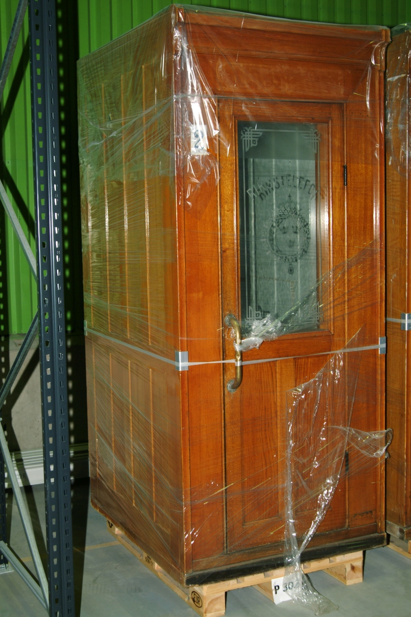 Talhytt för betjänad telefonstation, hytten märkt "2". Framsida i polerad ek, glas i dörr med riksvapen och texten "Rikstelefon".