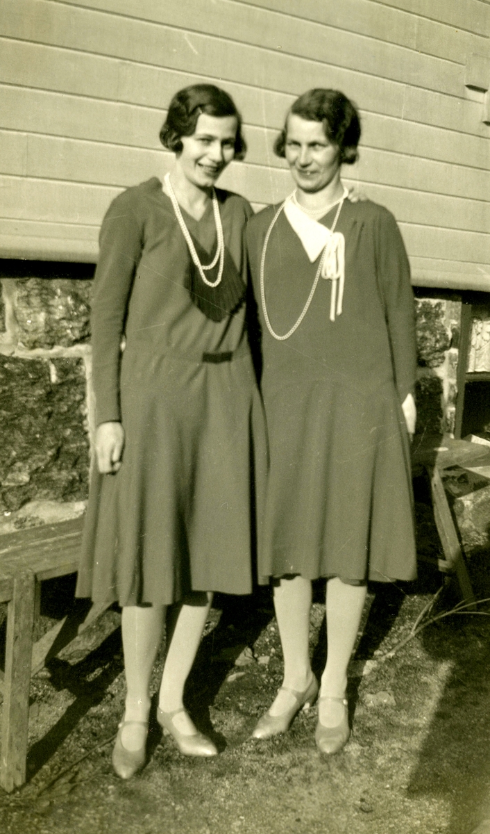 Systrarna Astrid (1907 - 1994, gift Jägerström) och Ingeborg Gustafsson (1901 - 1987, gift Johansson) står tillsammans utanför hemmet Kållered Stom "Nygård", okänt årtal.