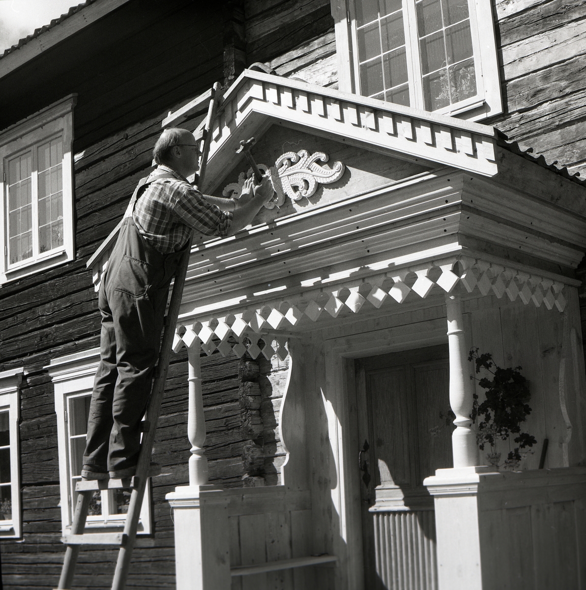 En man står på en stege och snickrar på brokvisten. TVinspelning om brokvistar, Hymmersbacken 1981.