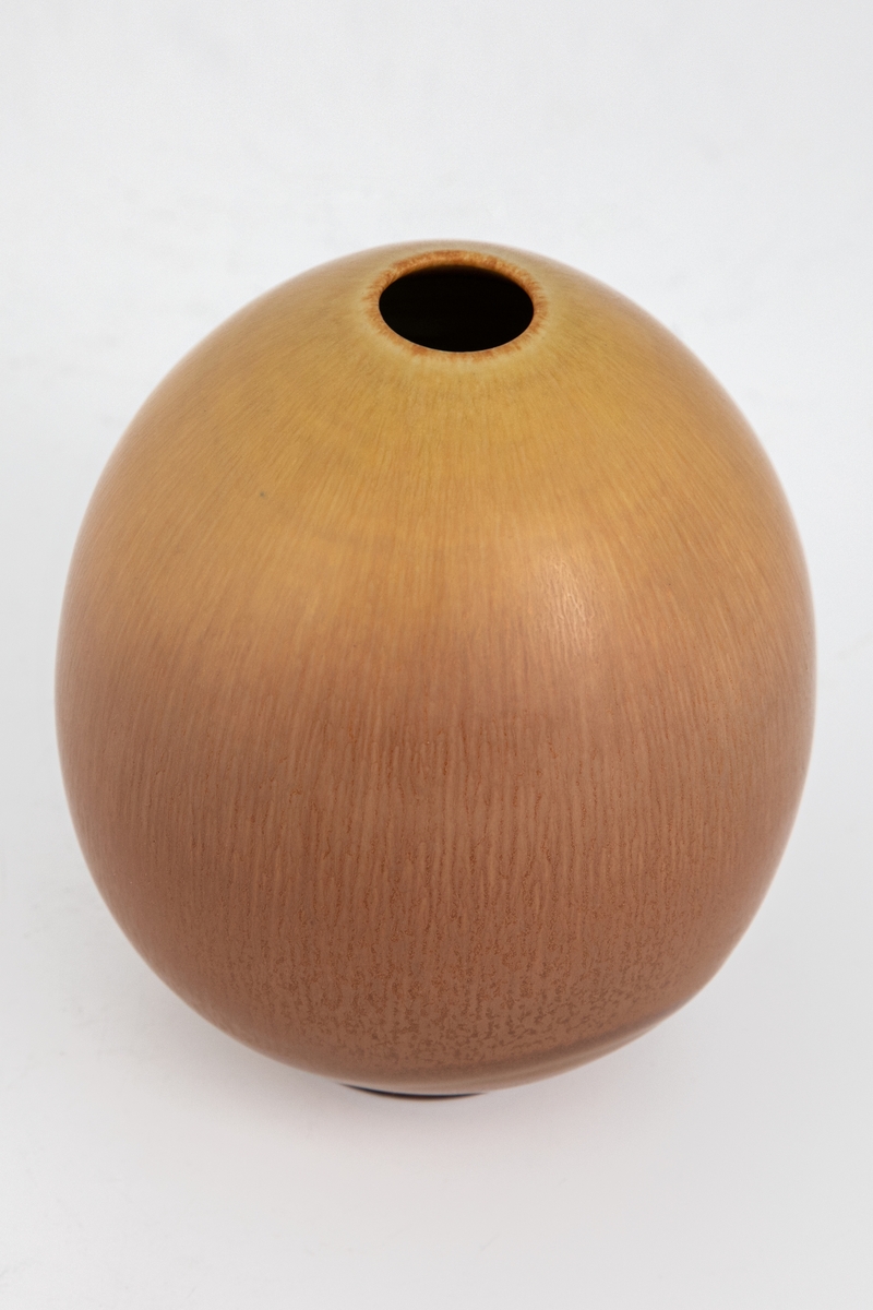 Liten eggformet vase med lav fot. Dreid steingods glasert med gulbrun harepelsglasur.