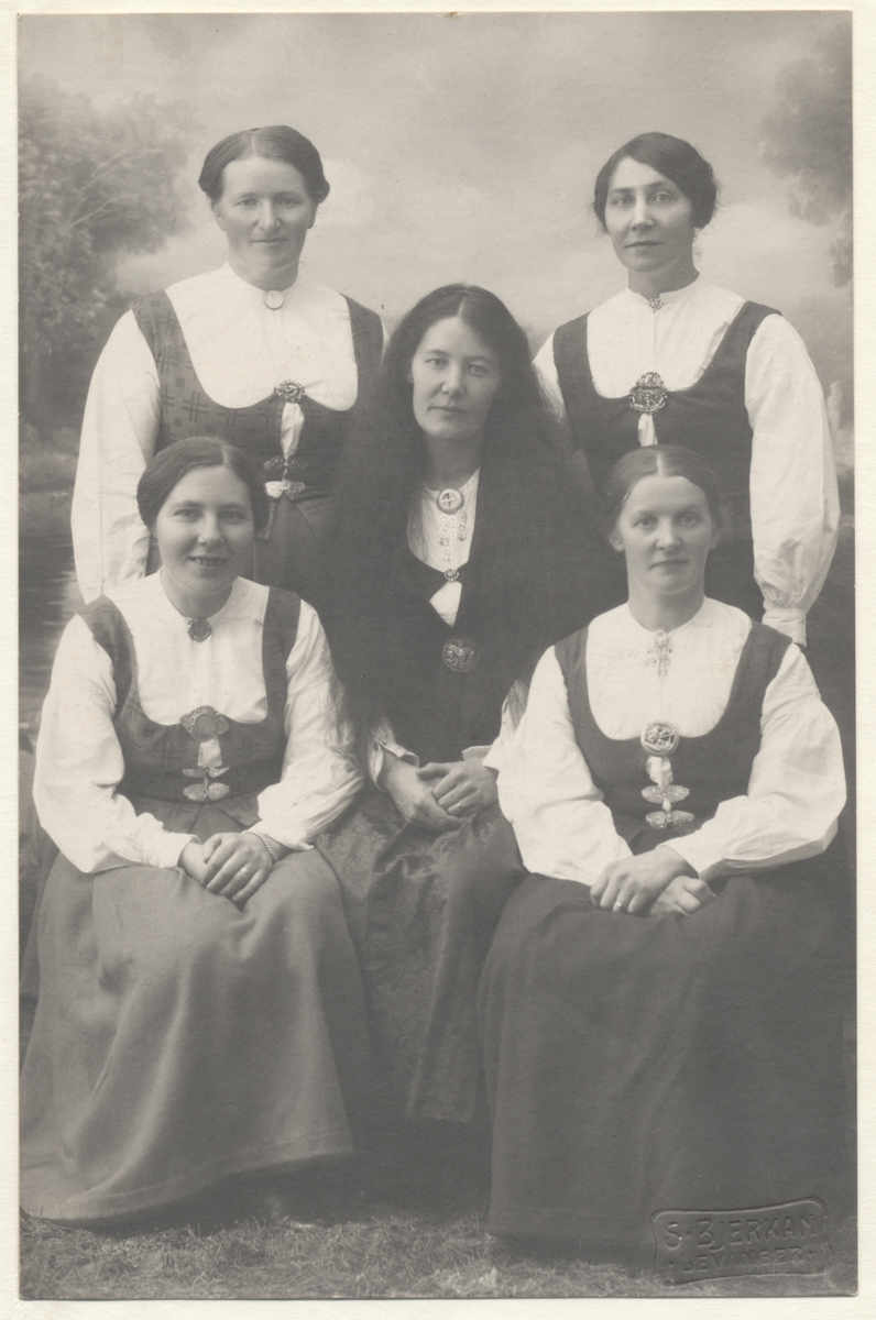 Fem kvinner, flere i nasjonaldrakt. På baksida julehilsen til «Lærer Harstad» fra «Anna, Ingeborg, Alette». Trolig tilknytning til Falstad skolehjem på Ekne.