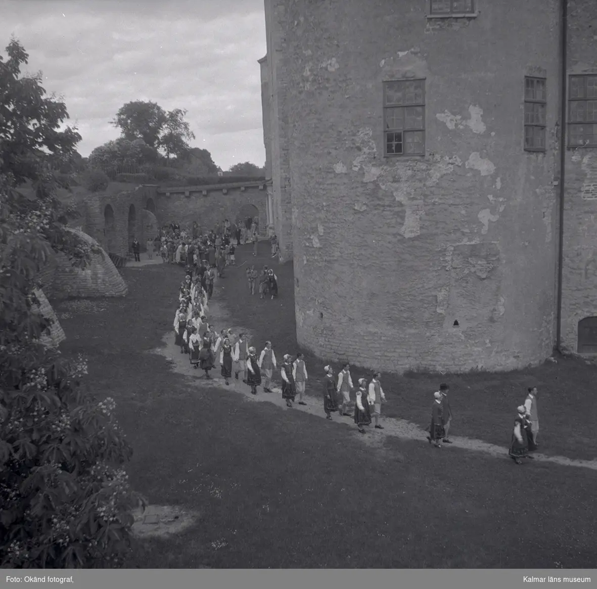 Människor som vandrar i folkdräkter på Kalmar slott. Orkester som spelar med violiner.