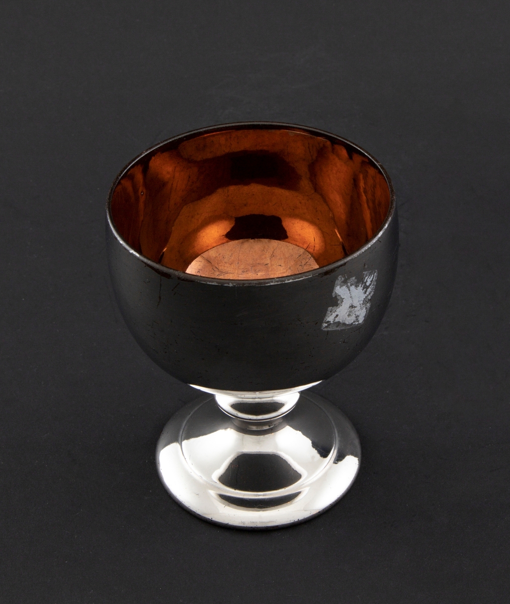 Sukkerskål i keramikk, glasert med sølvfarget luster på utsiden og gullfarget luster på innsiden av skålen. Halvkuleformet kupa, som hviler på en stett med ringformet vulst og sirkulær fotplate.