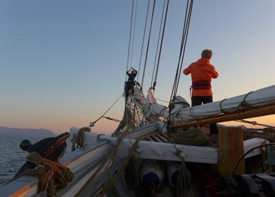 Men står utkikk forut i en seilbåt i soloppgang.. Foto/Photo