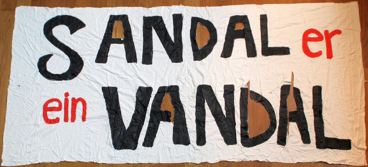 Banner frå arkivet til Norsk Målungdom. På banneret står teksten: "Sandal er ein vandal". Det er truleg at banneret har vore i bruk under ein aksjon for Norsk Målungdom.