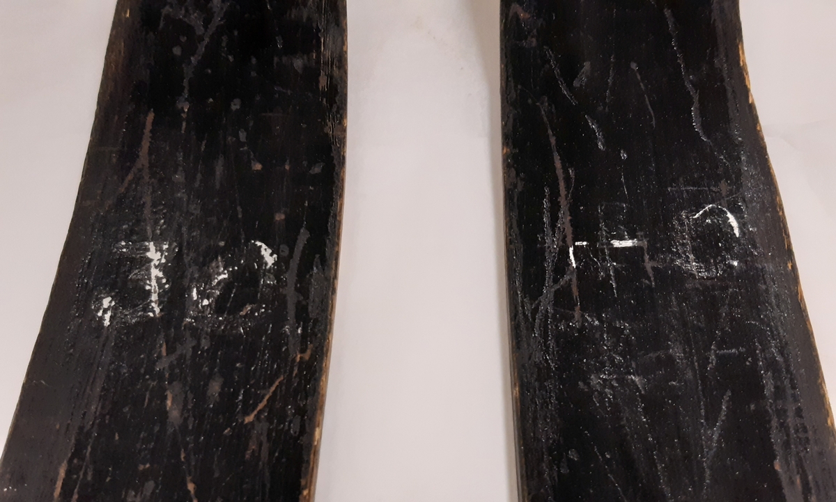Längdskidor, ett par, i svart trä med fotplattor samt skidbindning av läder och metall. Vid vardera bindning märkt "F 17". Samt vita färgrester av nummer "30" vid vardera skidspets.