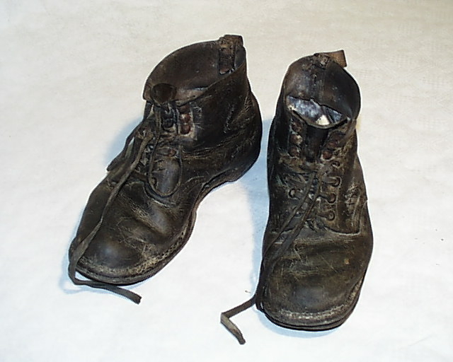 Herrestøvler av lær med bomull skolisser.
Støvlene har flere lærlapper med små spiker på sålene. Det ligger avispapir inni.