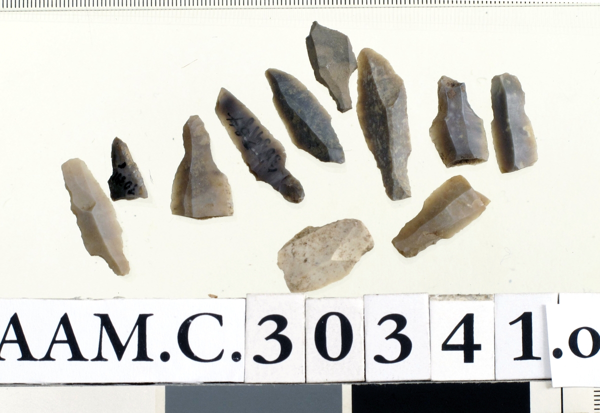3 hele og 8 fragmentariske, simple flekkepiler av mørk og lys grå flint, nærmest som Rogalands Stenalder, fig. 178-79 og 291. 

Lengde 1,6-3,7 cm. 

(A. 1784, 1786, 1870 b, 2209, 2210).
