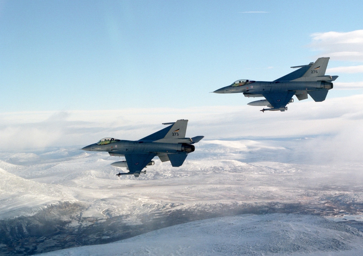 To F-16 over fjellandskap.