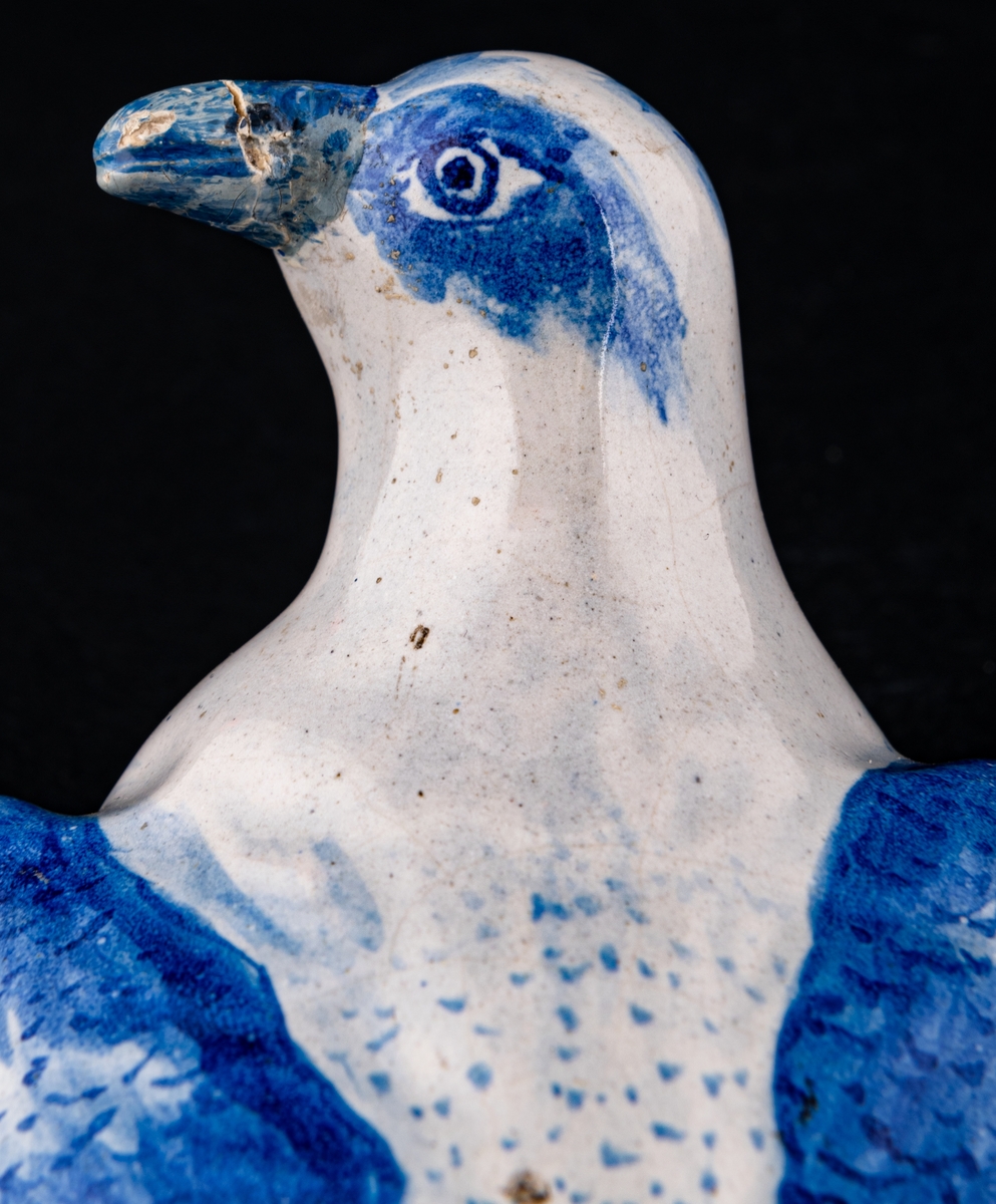 Smörask i form av fågel, blåvit fajans. s.k. smörduva.
Stämpel: MB. B (Marieberg, Berthevin).