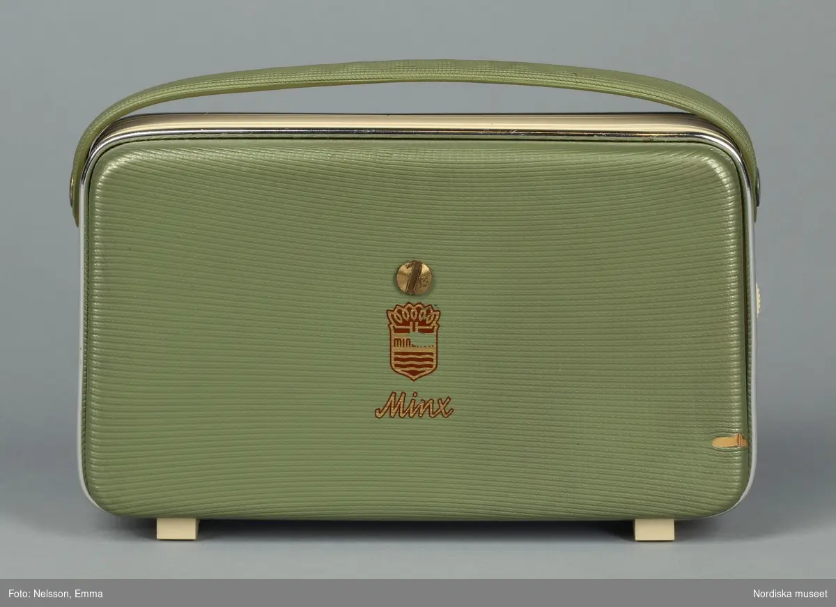 Huvudliggaren:
Radioapparat, transistor; grönvit med bärhandtag; rund programväljare på framsidan; märke 'Minerva' (från Österrike); förvaras i originalpåse av plast och med bruksanvisning. Originalkartong av papp. Inköpt av givaren 1953."
