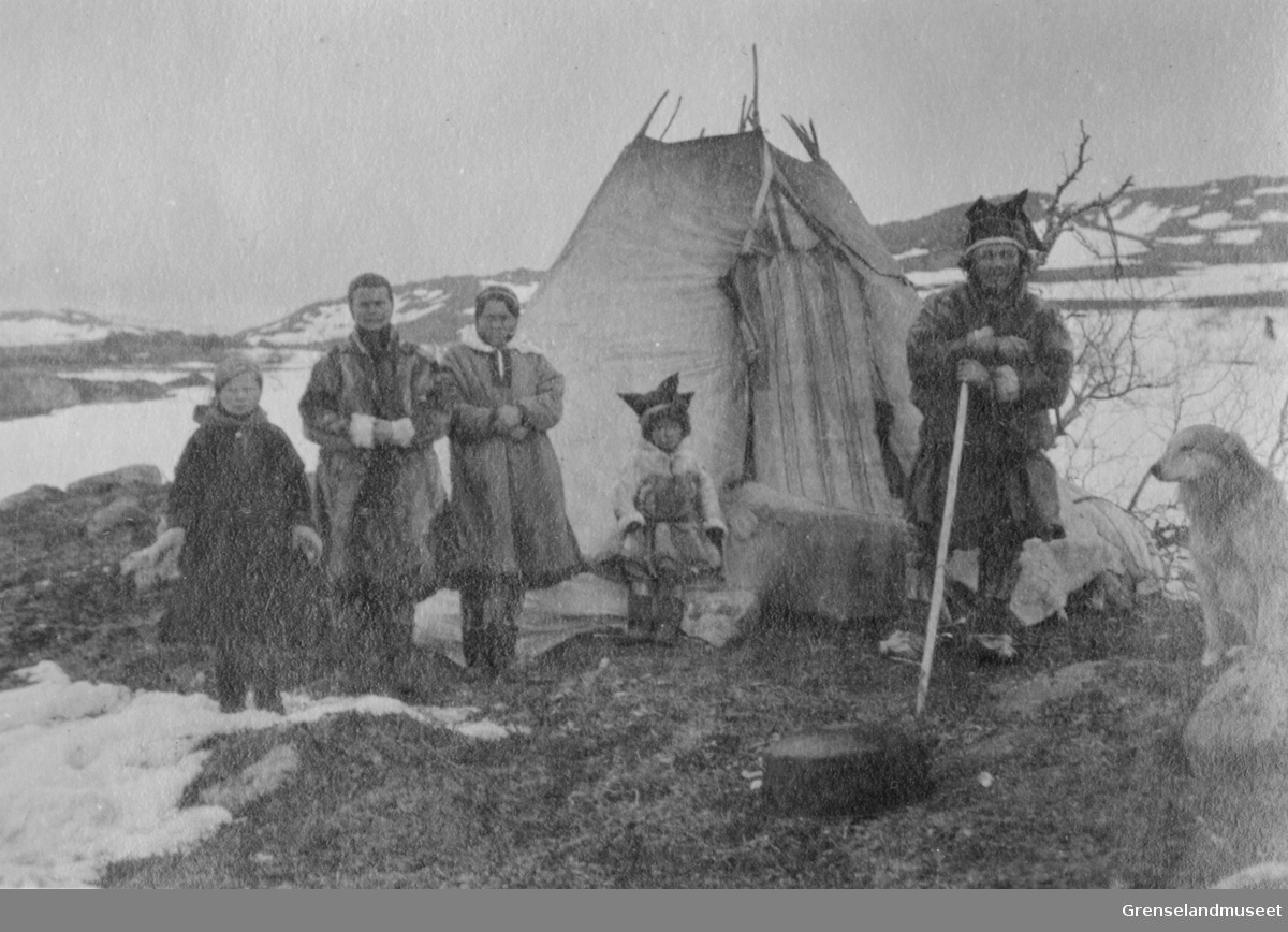 Samisk leir ved vann "186", Adamselv, 1919. En reindriftsfamilie står utenfor sin lavvo.