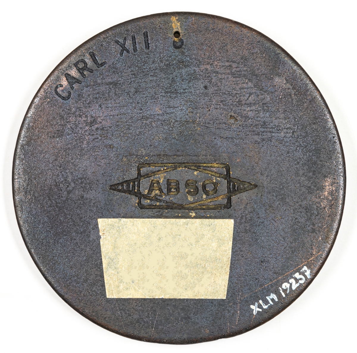 Medaljon, rund platta försedd med ett hål. Högerprofil, bröstbild av Carl XII. På baksidan djuprelief Carl XII och märket ABSO.
