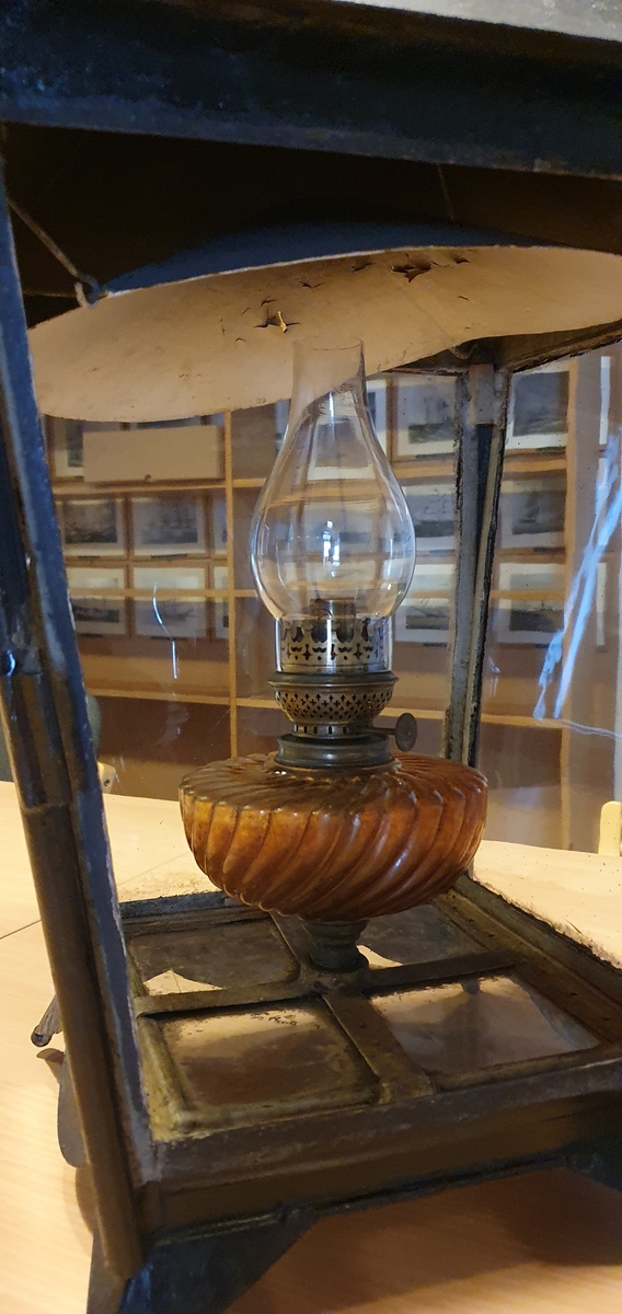 Parafinlampe, brukt som gatelykt i Mandal. Lykten har kvadratisk grunnform og rosa oljebeholder.
