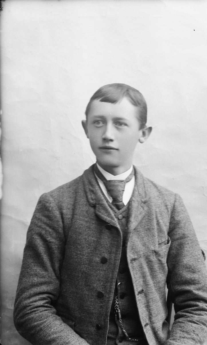 Ung mann i halvfigur med pannelugg, kledd i vest og jakke