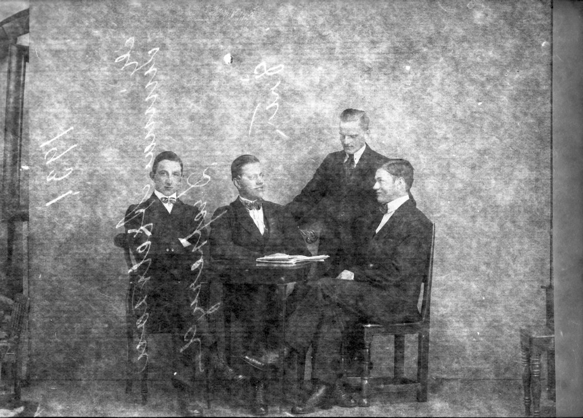 Fyra unga män sitter respektive står runt ett litet bord där det ligger en tidning. Till vänster sitter Herbert Jansson från Udderyd och den stående mannen är Gunnar Axelsson från Drevseryd.