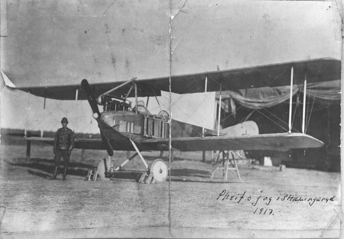En militärflygare står framför flygplan SW 12 vid en hangar, 1917.