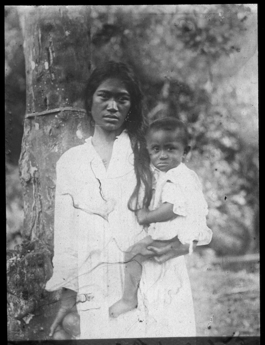 Bilden visar en kvinna med barn på famnen på Tahiti.