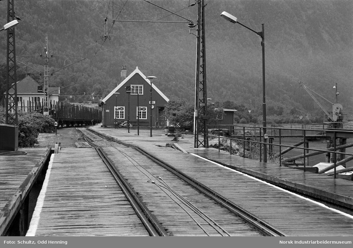 Jernbanestasjonen på Mæl eller Mæl stasjon sett fra sporet som leder ut til fergen, og et tog med jernbanevogner for transport av sekker.