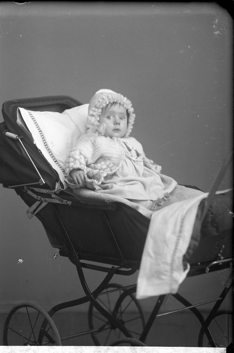 Porträtt av ett spädbarn i en barnvagn.
