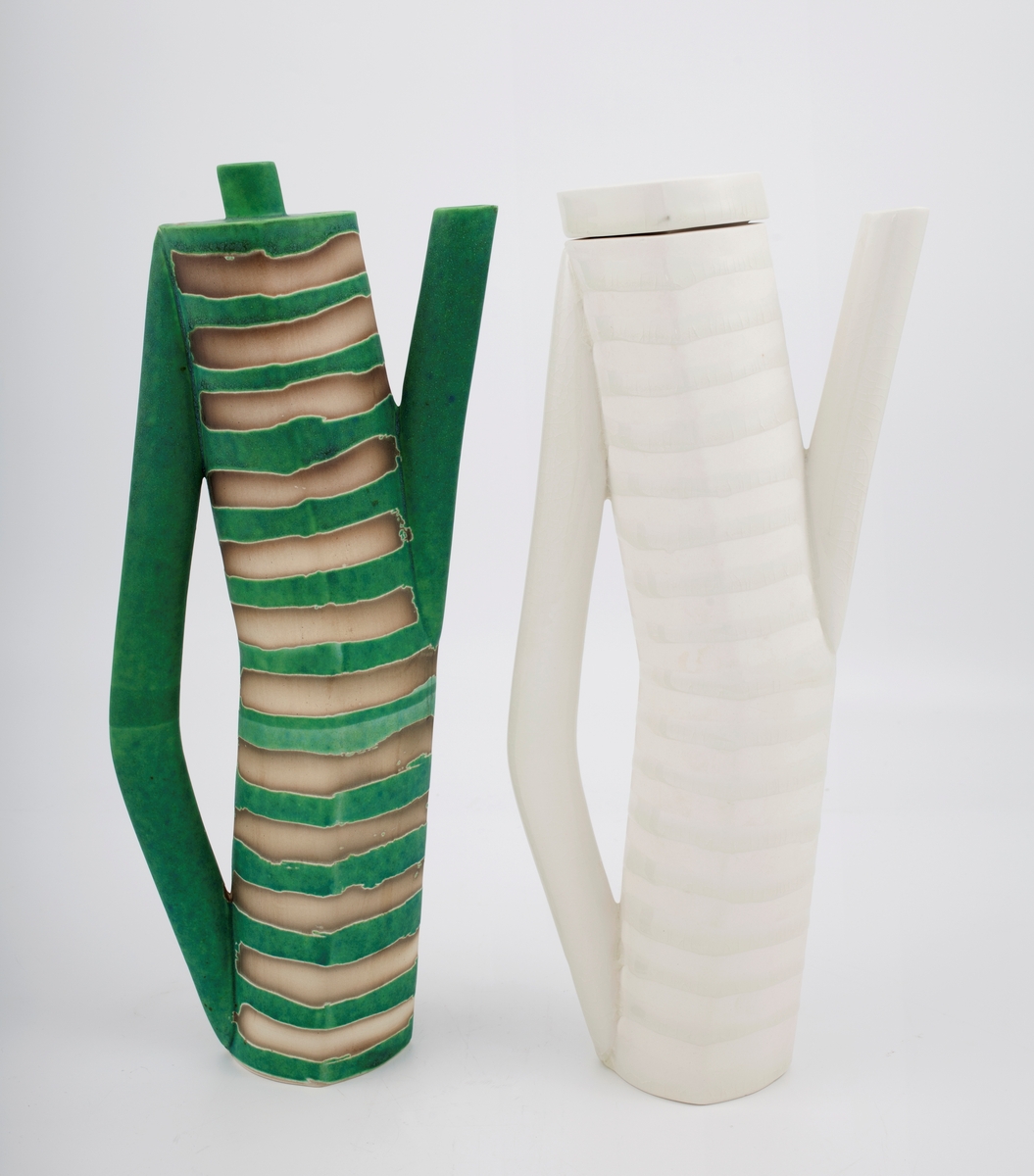 To høye, smale kanner med hank, tut og lokk. Glasert med henholdsvis grønn og hvit glasur på hank, tut, lokk og i horisontalt stripemønster på korpus, vekslende med uglaserte striper.