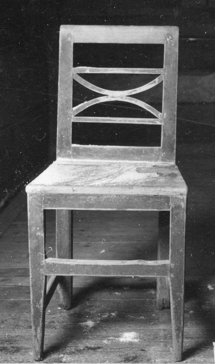 Brunmålad stol med genombruten rygg och med 4 horisontella spjälor av vilka de mellersta är böjda och kopplade. Raka 4-sidiga ben med tvärslåar.