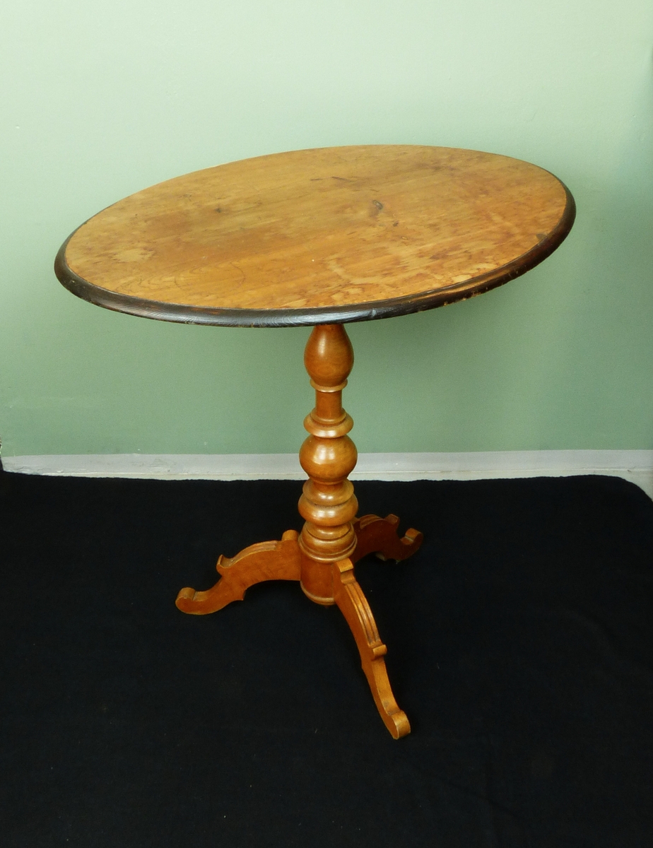 Pelarbord. Oval bordsskiva av trä. Svarvad pelare med fyra fötter går ner från bordets mitt.