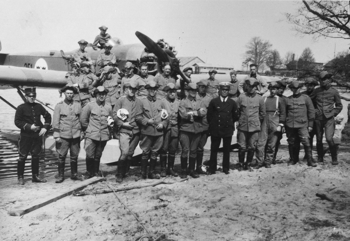 Gruppbild av ett större militärt manskap framför flygplan S 5, Heinkel He 5 Hansa nummer 251 på vatten.